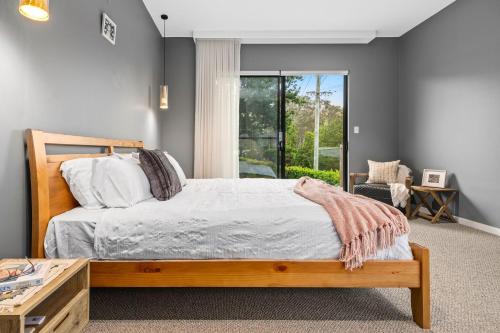 a bedroom with a wooden bed and a window at Magnolia House in Kurrajong