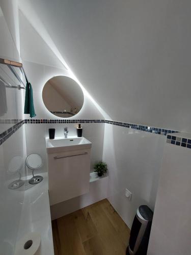 une salle de bain blanche avec un lavabo et un miroir dans l'établissement Gîte de Charme la Baudelliere, à Esvres