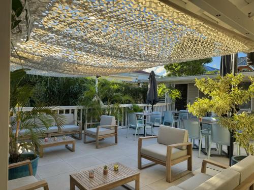a patio with chairs and tables and a ceiling with lights at Koho SXM - ex Hevea Hotel in Grand Case