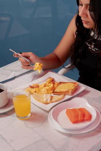 een vrouw die aan een tafel zit met een bord eten bij Hotel Kaamú Taganga in Taganga