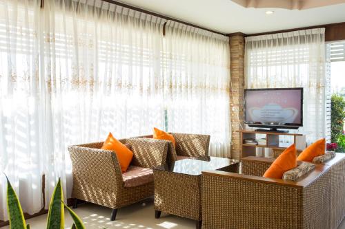 un soggiorno con sedie in vimini e TV di Khunyuw Hotel a Fang