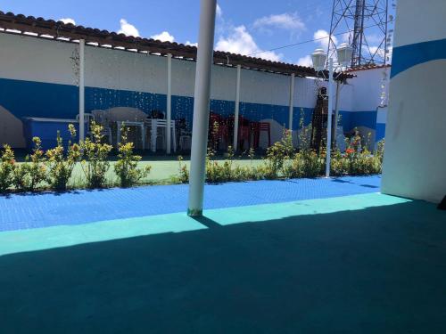 a blue and white building with a courtyard with flowers at kitnet & lazer in Pitimbu