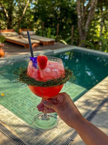 a person holding a drink with a strawberry in it at SITIO VILLA DA MATA in São Miguel dos Milagres