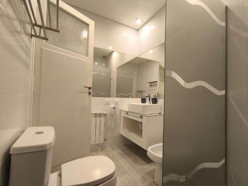 a white bathroom with a toilet and a sink at Céntrika in Mendoza