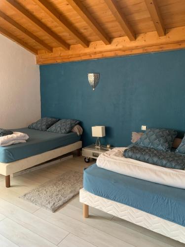 une chambre avec deux lits et un mur bleu dans l'établissement Gîte de la fontaine, à Sainte-Agathe