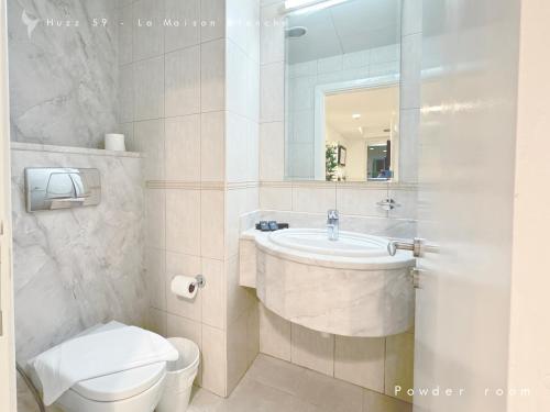 a bathroom with a sink and a toilet and a mirror at Huzz 59 - La Maison Blanche in Dubai