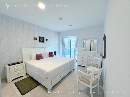 a white bedroom with a large white bed and a chair at Huzz 59 - La Maison Blanche in Dubai
