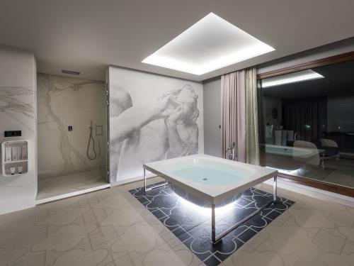 a bathroom with a tub and a painting on the wall at Hotel Spa Elia in Alcalá del Júcar