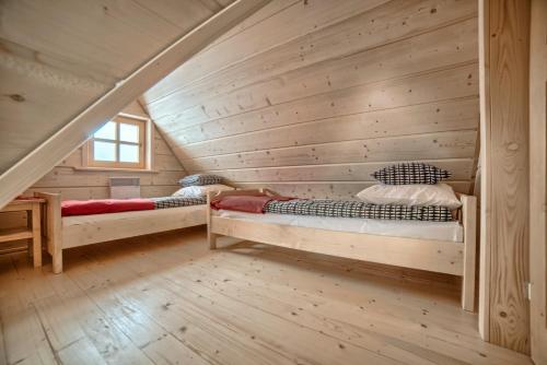 two beds in a room with a wooden wall at Domek NBD-bafia in Zakopane