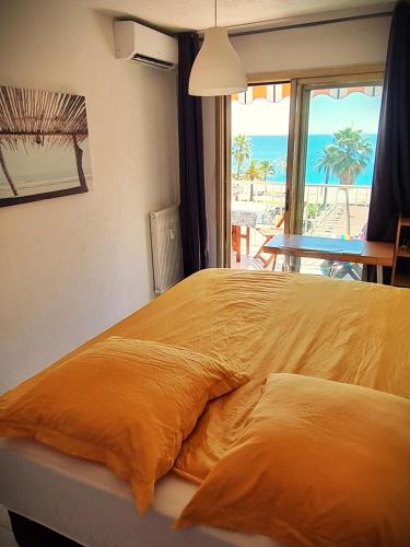 - un lit avec une couette en orange et une vue sur la plage dans l'établissement Nizza-Azur vue mer, à Nice