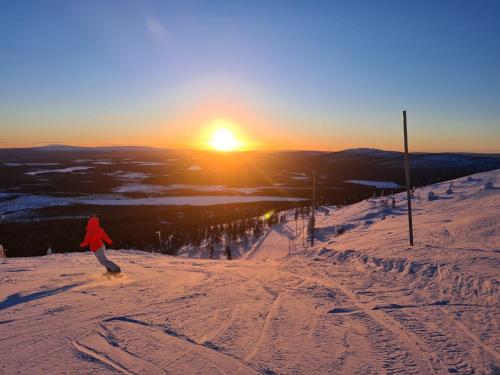 a person riding a snowboard down a snow covered slope at sunset at Saana's chalets Levi in Levi