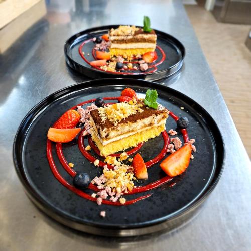 two black plates with cake and fruit on a counter at Berghotel zum Zirm in Collalbo