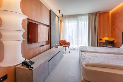 a hotel room with a bed and a tv at LLAC Living Nature Hotel in Limone sul Garda