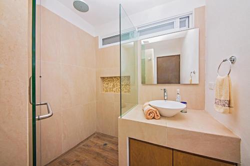 a bathroom with a sink and a glass shower at Casa CAMPANA, Privada, Piscina Privada, 3 Cuadras Malecón in Cozumel