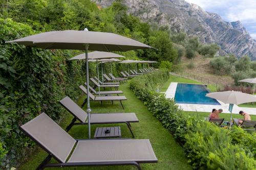 a row of lounge chairs with umbrellas next to a pool at LLAC Living Nature Hotel in Limone sul Garda
