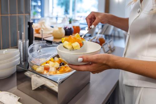 a woman holding a bowl of fruit on a counter at LLAC Living Nature Hotel in Limone sul Garda