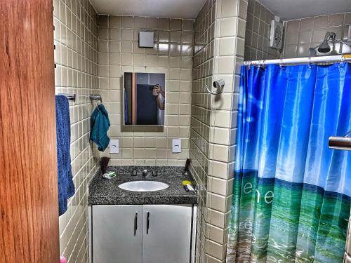 a bathroom with a sink and a blue shower curtain at Fabinhos SSA in Salvador