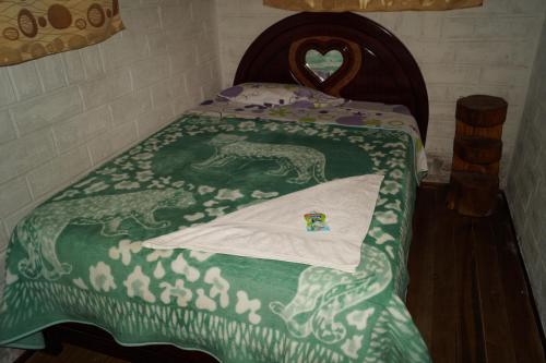a bed with a green blanket with a horse on it at Hostal La Rosita in Chugchilán