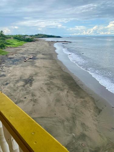 a view of a beach with a yellow bench at Casa Lassini, Oceanfront Lodging, Playa Las Comadres in Las Cucharitas