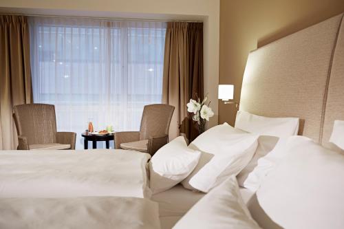 a hotel room with a bed and chairs and a window at Lindner Hotel Antwerp, part of JdV by Hyatt in Antwerp