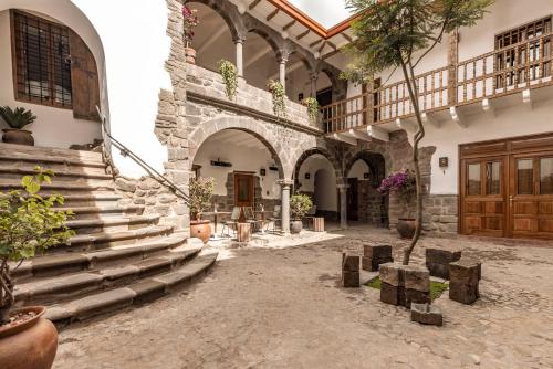 a courtyard with stairs and a building with wooden doors at Casa Clara by Ananay Hotels in Cusco