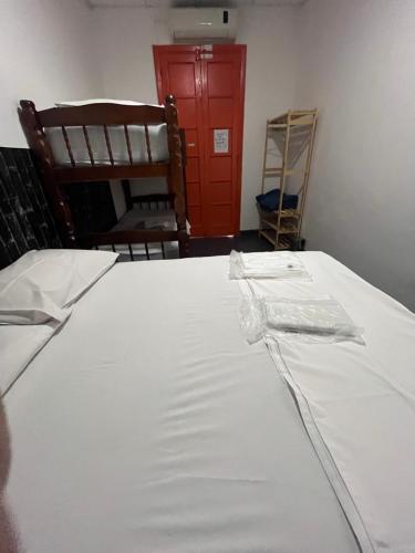 a bed with a white sheet and a red cabinet at COACHHOSTEL7 in Sao Paulo