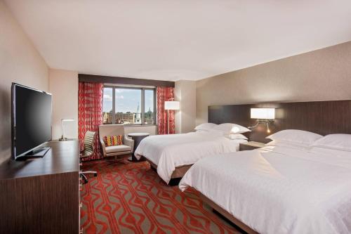 a hotel room with two beds and a flat screen tv at Sheraton Springfield Monarch Place Hotel in Springfield