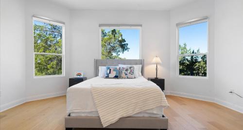 a white bedroom with a bed and three windows at Tranquil Lakefront Villa - Perfect for Weekdays or Weekends in South Jonestown Hills