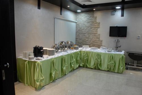 a long table with a green table cloth in a room at Al Hayat Hotel Suites in Sharjah