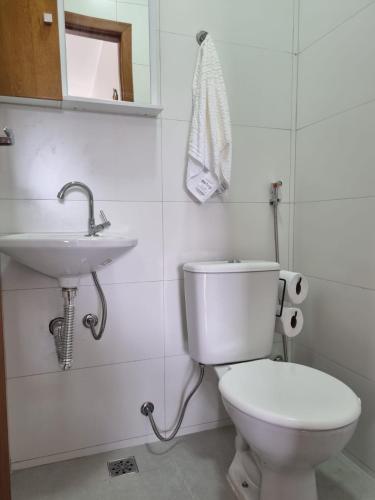 a bathroom with a white toilet and a sink at Jacarandá de Minas Vista Mar Praia de Meaipe Guarapari in Guarapari