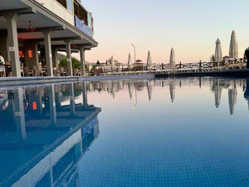 a pool of water with tables and umbrellas at Suhan Seaport Hotel in Kusadası