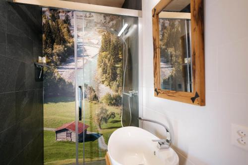 une salle de bain avec un lavabo et une douche avec une fenêtre dans l'établissement Apartment Strohballenhaus, à Amden