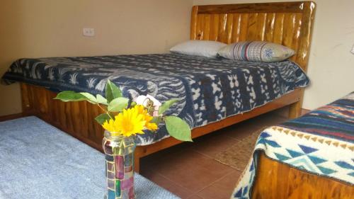 a bedroom with a bed and a vase with flowers in it at Casa Hotel Loma Wasi en Cotacachi in Cotacachi