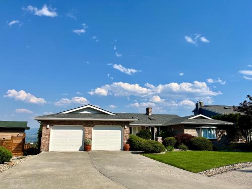a house with two white garage doors in a driveway at Lake and the City Bed and Breakfast in West Kelowna