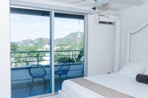 a bedroom with a bed and two chairs on a balcony at Hotel Kaamú Taganga in Taganga