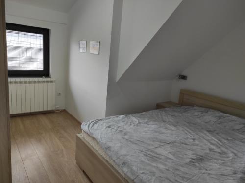 a white bedroom with a bed and a window at Gorštak in Kopaonik
