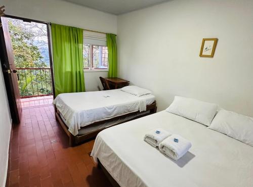 een slaapkamer met 2 bedden en een raam met groene gordijnen bij Eco Lodge La Juanita in Manizales