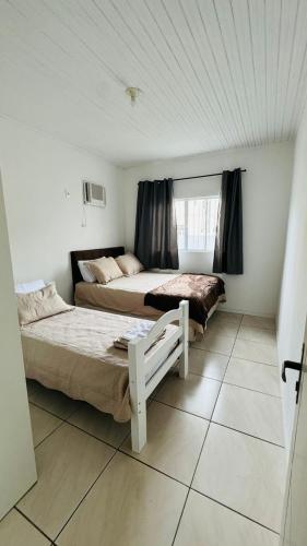 a bedroom with two beds and a window at Bembella casa em Balneario Camboriu in Balneário Camboriú