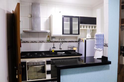a kitchen with white cabinets and a black counter top at Casa Caminho da fé a menos de 10 minutos da basílica in Potim