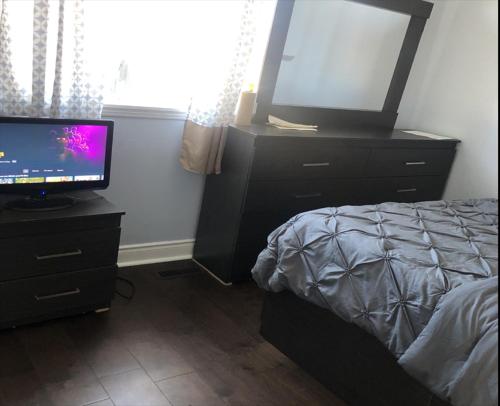 a bedroom with a bed and a television on a dresser at SHAY 2ND FLOOR-Holiday Home in Pickering