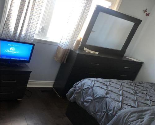 a bedroom with a bed and a television on a dresser at SHAY 2ND FLOOR-Holiday Home in Pickering