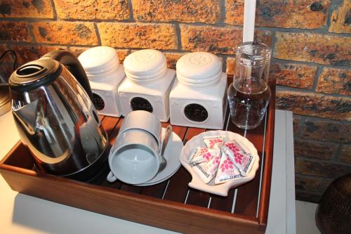a wooden tray with utensils and a tea set at Quest Bed And Breakfast in Melkbosstrand