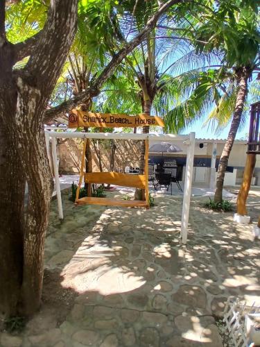 a bench under a tree with a sign on it at Sharick Beach House in Tubará