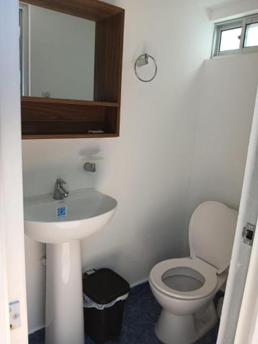 a bathroom with a toilet and a sink and a mirror at Sharick Beach House in Tubará