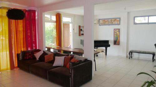 a living room with a couch and a piano at Villa Pointe La Rose in Le Robert
