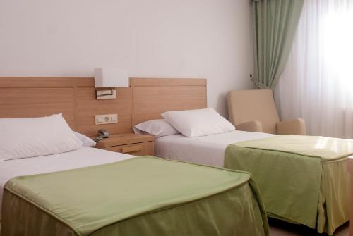 a hotel room with two beds with green sheets at Hotel El Duende in Cambados