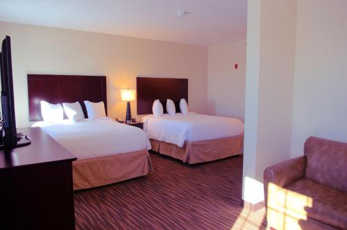 a hotel room with two beds and a couch at Cobblestone Inn & Suites - Holstein in Holstein