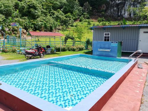 a swimming pool with a motorcycle parked next to it at Bekbek's Village in Kangar
