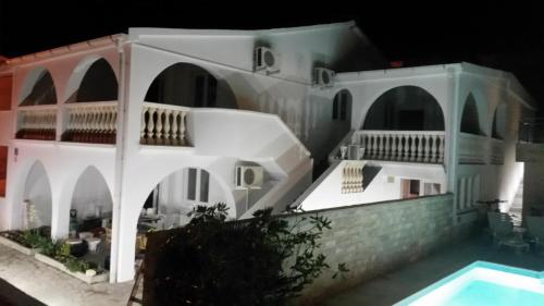 a white house with a swimming pool at night at Apartments "I & I" in Pag