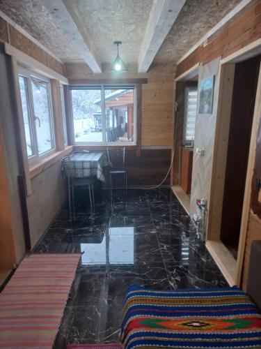a room with a tile floor with a table and windows at Садиба Федорчуків За рікою1 in Sheshory